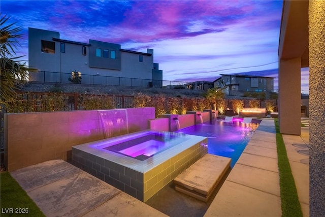 patio terrace at dusk featuring an in ground hot tub and fence