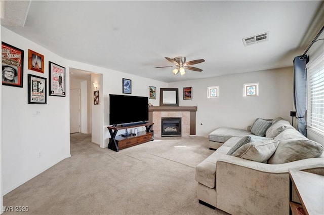 carpeted living room with a fireplace and ceiling fan