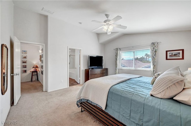 bedroom featuring ceiling fan, ensuite bath, light carpet, and lofted ceiling