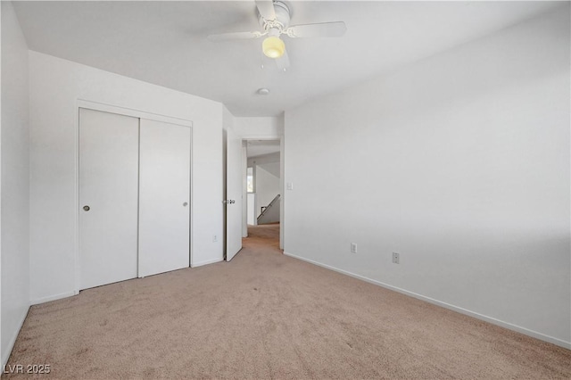 unfurnished bedroom featuring a closet, light colored carpet, and ceiling fan