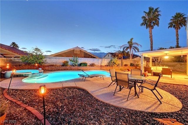 pool at dusk featuring an in ground hot tub and a patio area