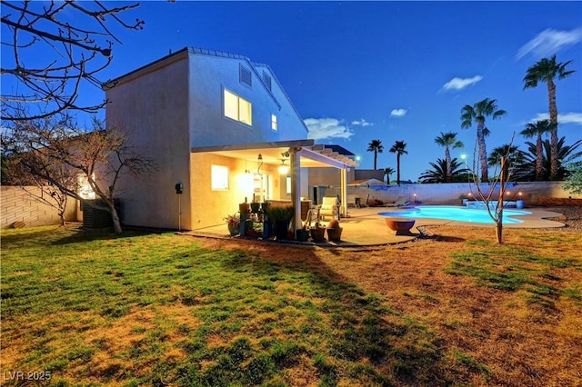 back of property with a patio, a yard, and a fenced in pool