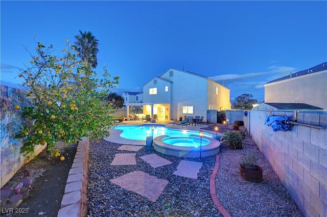 pool at dusk with a patio and an in ground hot tub