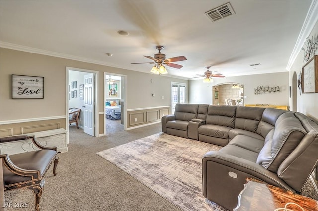 carpeted living room with ceiling fan and ornamental molding