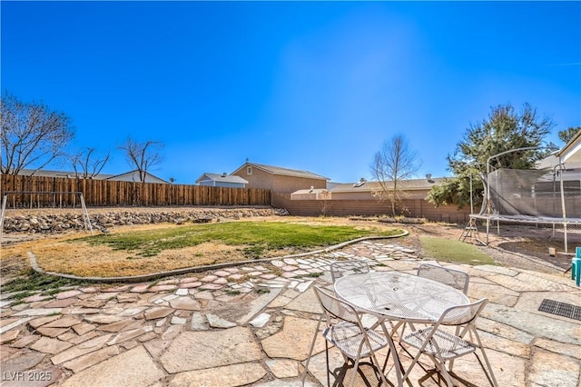 view of yard with a trampoline and a patio area