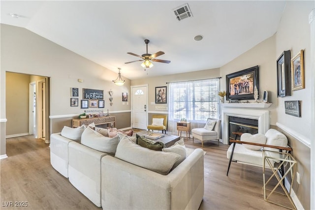 living room featuring lofted ceiling, ceiling fan, and light hardwood / wood-style flooring