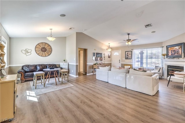 living room with ceiling fan, lofted ceiling, and light hardwood / wood-style floors