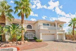 mediterranean / spanish home featuring a garage and a balcony