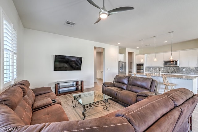 living room featuring light hardwood / wood-style flooring and ceiling fan