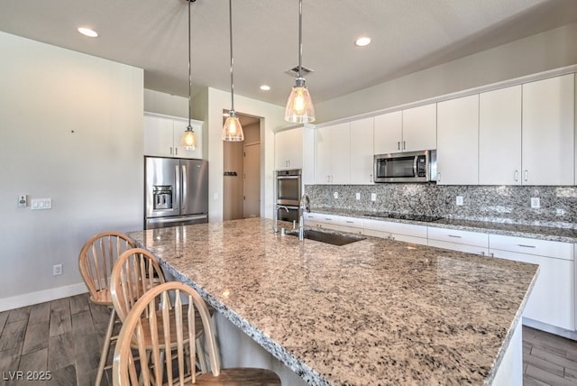 kitchen with a center island with sink, appliances with stainless steel finishes, white cabinetry, and backsplash