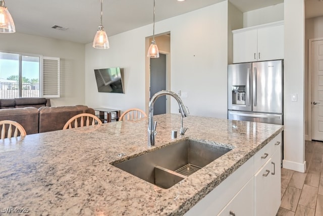 kitchen with white cabinets, sink, light stone counters, and stainless steel fridge with ice dispenser