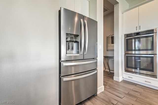 kitchen featuring appliances with stainless steel finishes, light hardwood / wood-style flooring, and white cabinets