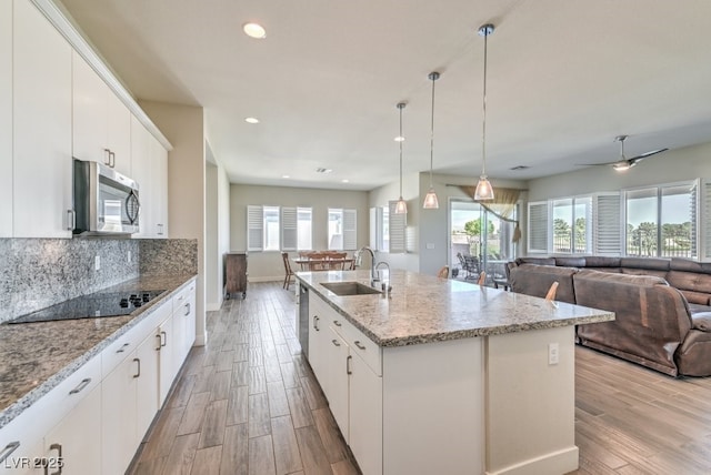 kitchen with white cabinets, an island with sink, stainless steel appliances, and sink