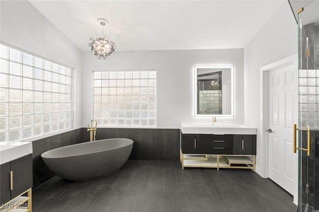 bathroom with vanity, tile patterned flooring, a tub, and an inviting chandelier