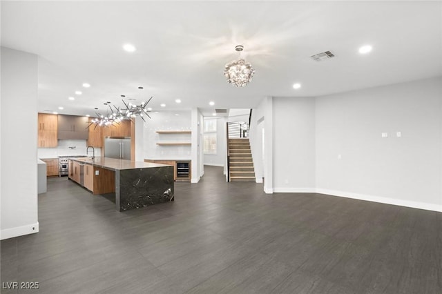 unfurnished living room featuring sink, dark hardwood / wood-style flooring, and a notable chandelier