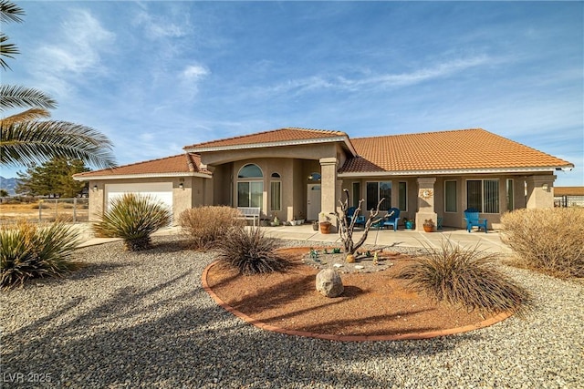 view of front of home with stucco siding, a tile roof, and an attached garage