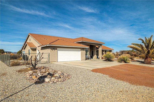 view of front of property featuring stucco siding, a tiled roof, fence, a garage, and concrete driveway