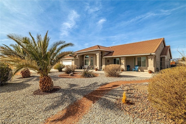 view of front of house featuring stucco siding, a tiled roof, and an attached garage