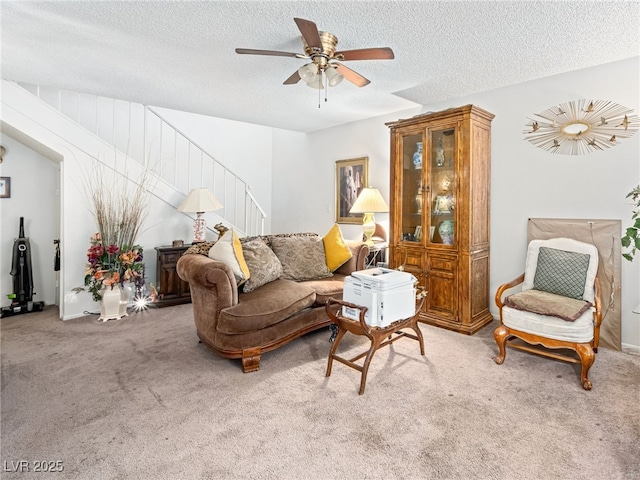 carpeted living room featuring ceiling fan and a textured ceiling