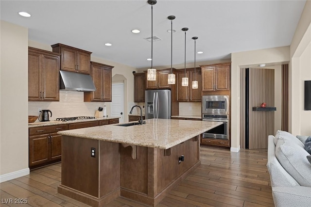 kitchen featuring under cabinet range hood, stainless steel appliances, dark wood-style flooring, a sink, and visible vents