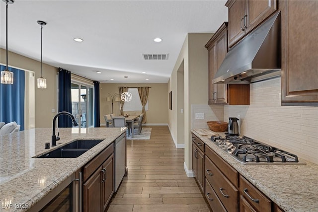 kitchen featuring tasteful backsplash, visible vents, stainless steel appliances, under cabinet range hood, and a sink