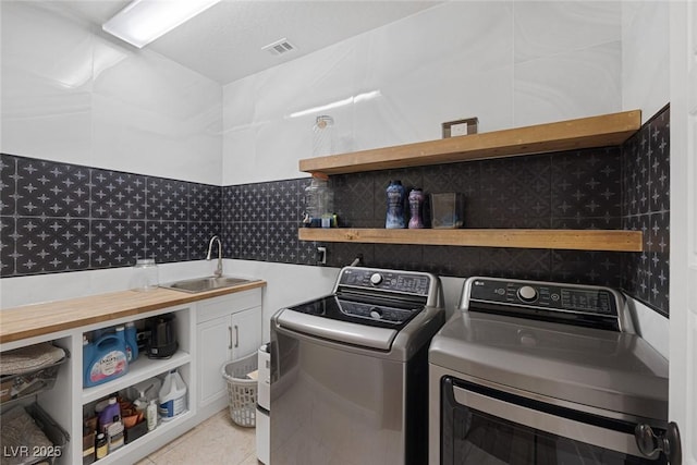 clothes washing area featuring visible vents, light tile patterned flooring, a sink, and cabinet space