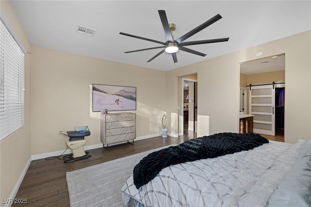 bedroom featuring a barn door, visible vents, baseboards, a ceiling fan, and hardwood / wood-style flooring