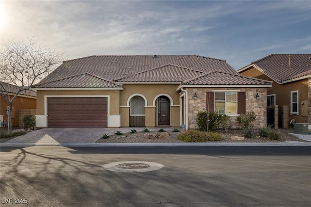 view of front of home with a garage, decorative driveway, a tile roof, and stucco siding