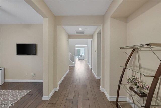 hallway with baseboards, visible vents, hardwood / wood-style floors, and stairs