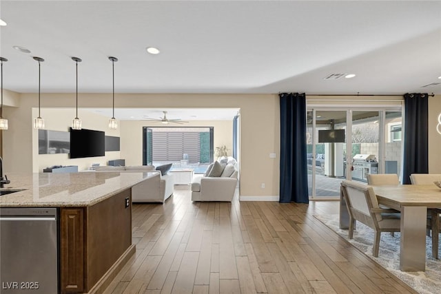 kitchen with light stone counters, open floor plan, a sink, wood finished floors, and dishwasher