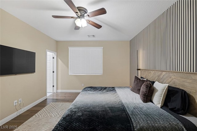 bedroom featuring ceiling fan, wood finished floors, visible vents, and baseboards