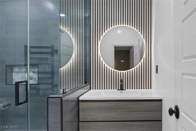 bathroom featuring a shower with door and vanity