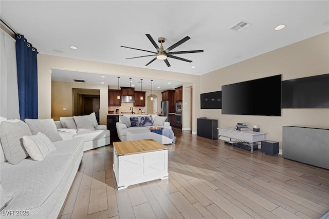 living area with ceiling fan, recessed lighting, wood finished floors, visible vents, and baseboards