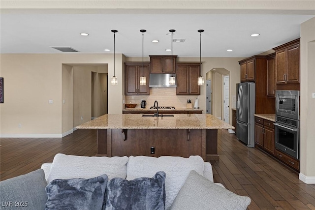 kitchen with arched walkways, visible vents, backsplash, appliances with stainless steel finishes, and under cabinet range hood