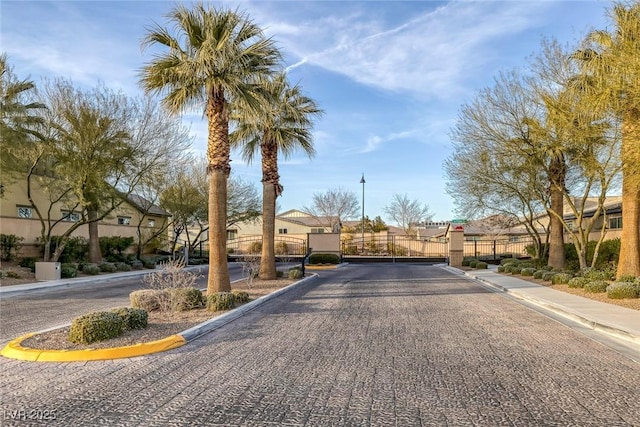 view of street featuring a residential view, a gated entry, curbs, a gate, and sidewalks