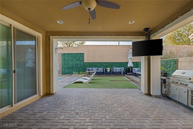 view of patio / terrace with area for grilling, fence, an outdoor living space, a ceiling fan, and exterior kitchen