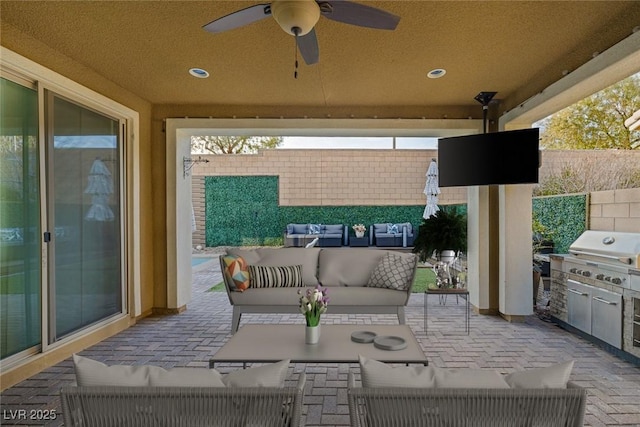 view of patio featuring ceiling fan, an outdoor kitchen, area for grilling, fence, and an outdoor living space