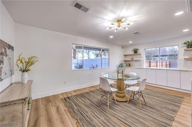 dining area with an inviting chandelier, plenty of natural light, and light hardwood / wood-style flooring