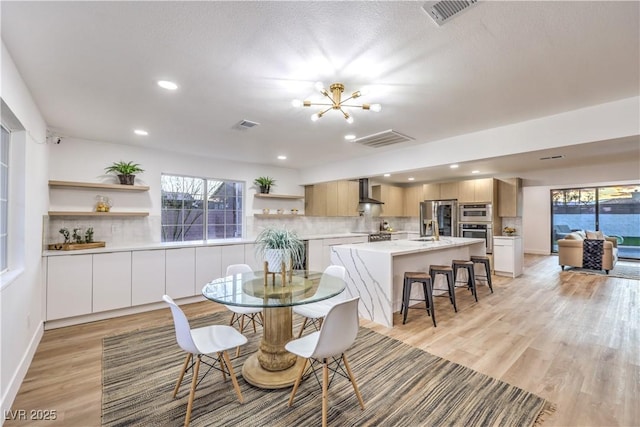 dining area featuring a healthy amount of sunlight, sink, an inviting chandelier, and light hardwood / wood-style floors