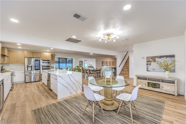 dining room with light wood-type flooring, sink, and a chandelier