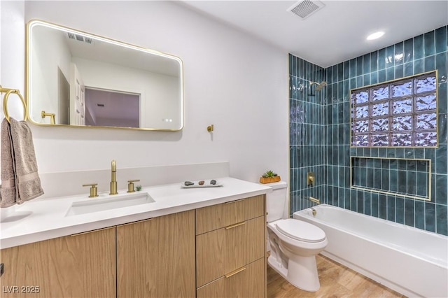 full bathroom with toilet, vanity, tiled shower / bath, and hardwood / wood-style floors