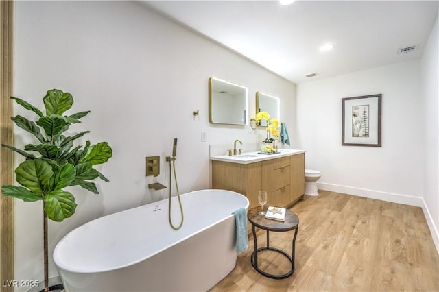 bathroom featuring toilet, vanity, a bathtub, and hardwood / wood-style flooring