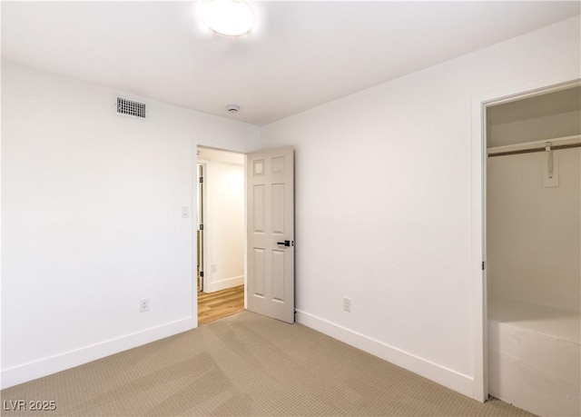 unfurnished bedroom with a closet and light colored carpet