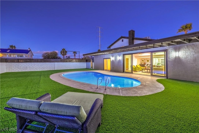 pool at dusk featuring a patio and a lawn