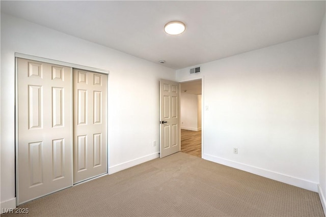 unfurnished bedroom with a closet and light colored carpet