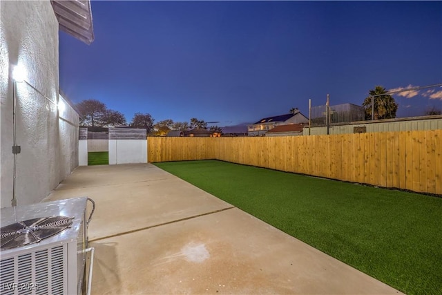 yard at dusk with cooling unit and a patio