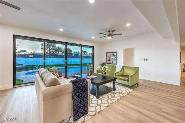 living room with light wood-type flooring, a water view, and ceiling fan