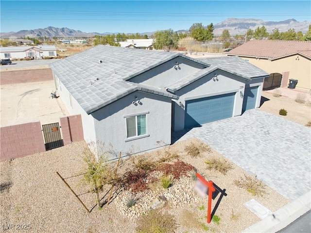 view of front of property featuring a mountain view, a garage, fence, decorative driveway, and stucco siding