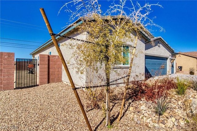 view of home's exterior featuring a garage, a gate, and stucco siding