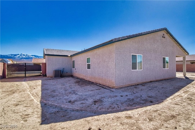 view of side of property featuring fence, a mountain view, cooling unit, and stucco siding